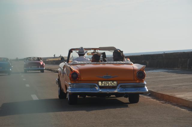 An orange convertible on the seafront road