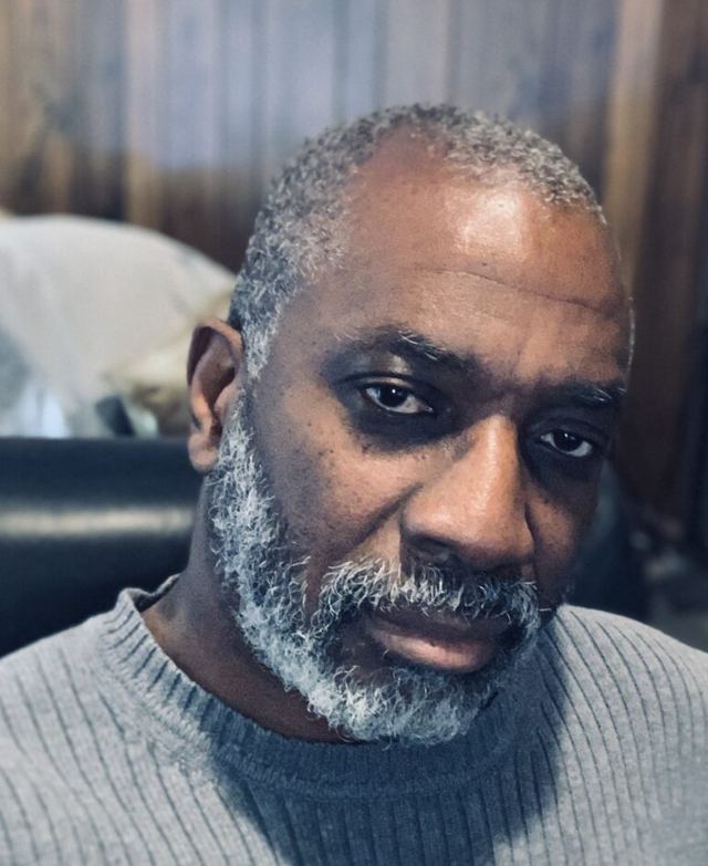 Portrait of a man with a grey beard wearing a grey sweater