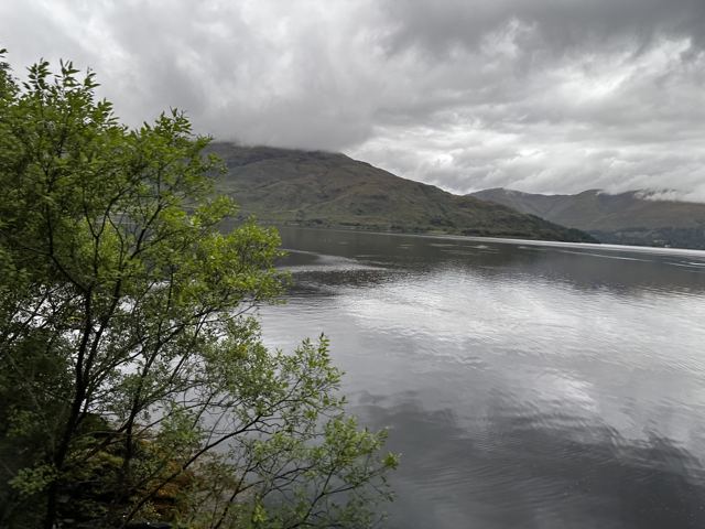 A still loch reflecting a grey sky