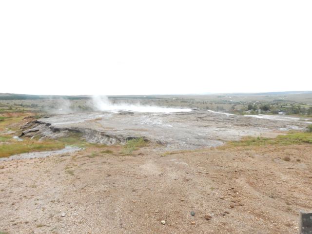 Steam rising from pale geothermal ground