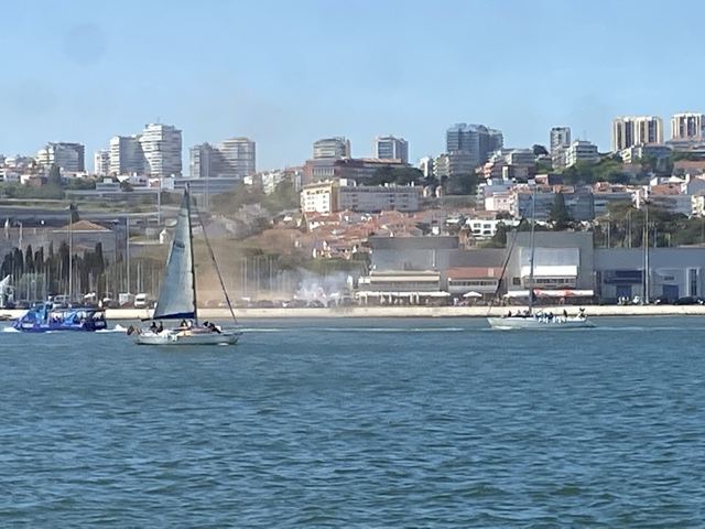 A sailboat on the river with the city behind