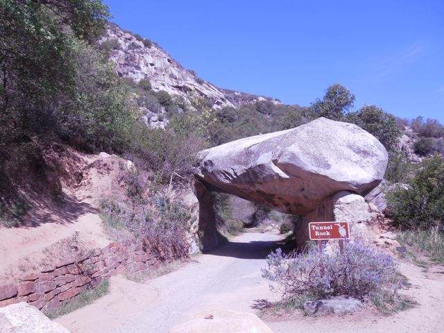 A boulder resting on a rock arch beside the road