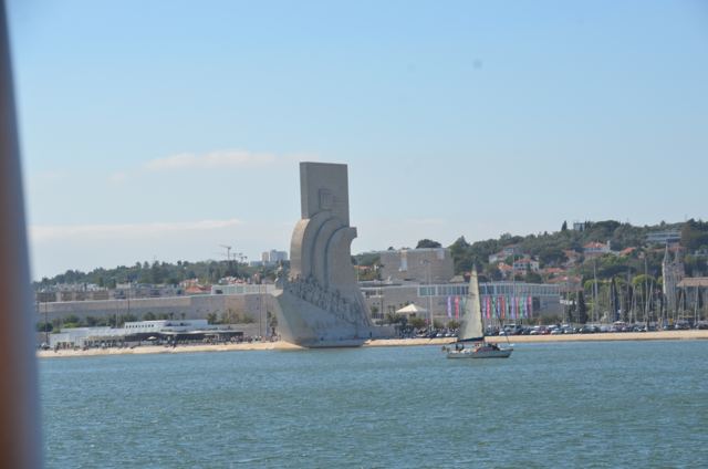 A white monument shaped like a ship's prow beside the river