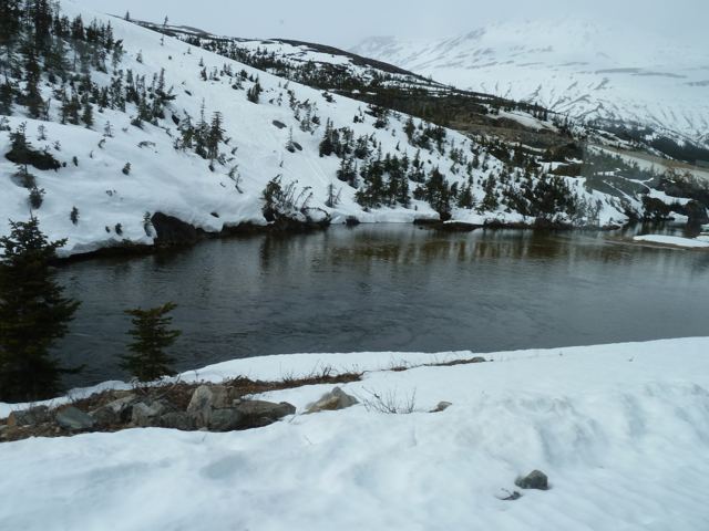 A frozen lake with snow on the slope