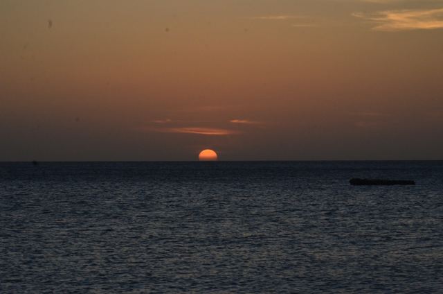 A red sun setting over a calm sea