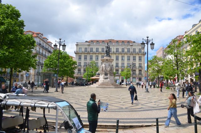 A plaza with a statue and cafe tables