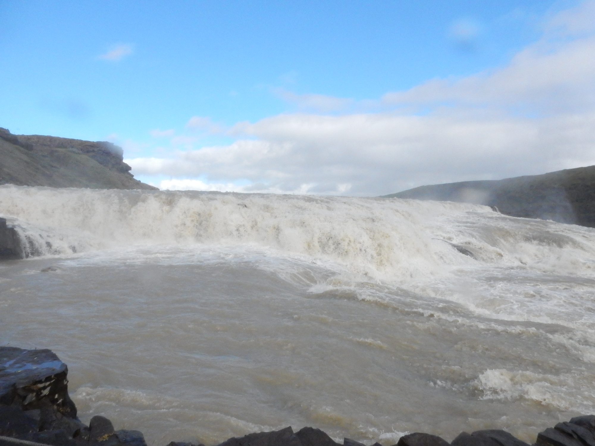 A wide waterfall under blue sky and clouds