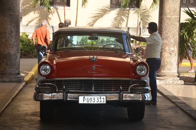 A red vintage car parked under palms