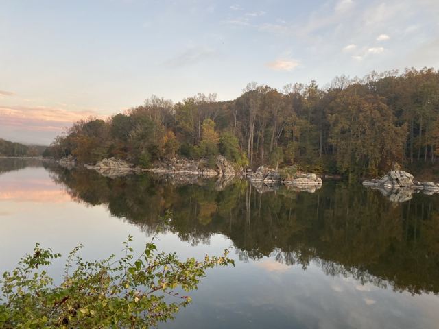 Autumn trees and rocks reflected in a still river at dusk