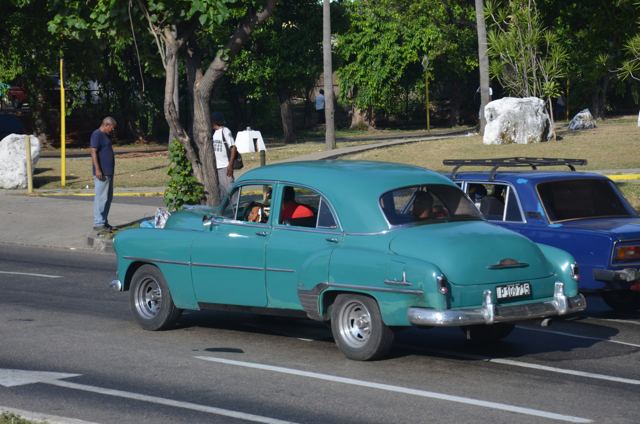 A teal vintage car on the road