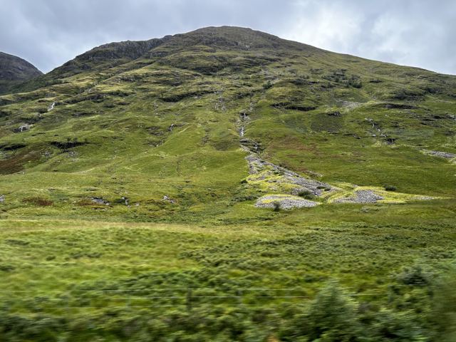 A grassy hillside with a path climbing to the ridge