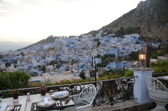 Terrace tables looking over the blue hillside town at dusk