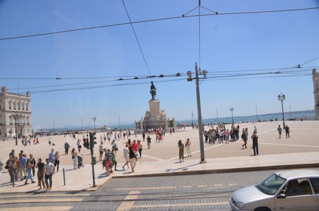 Tram wires over a busy square beside the river